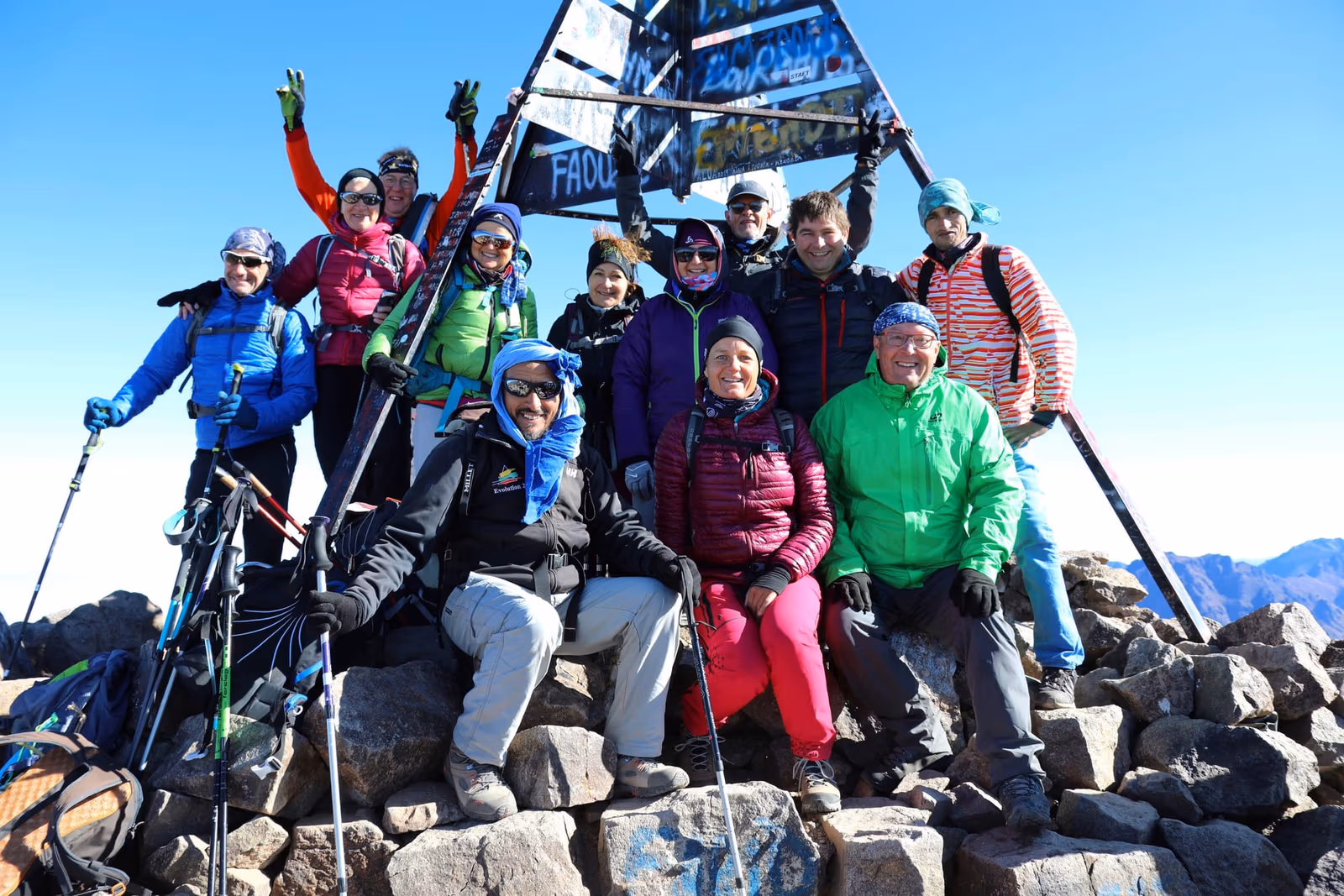 Trekkers raising their poles on the summit of Toubkal