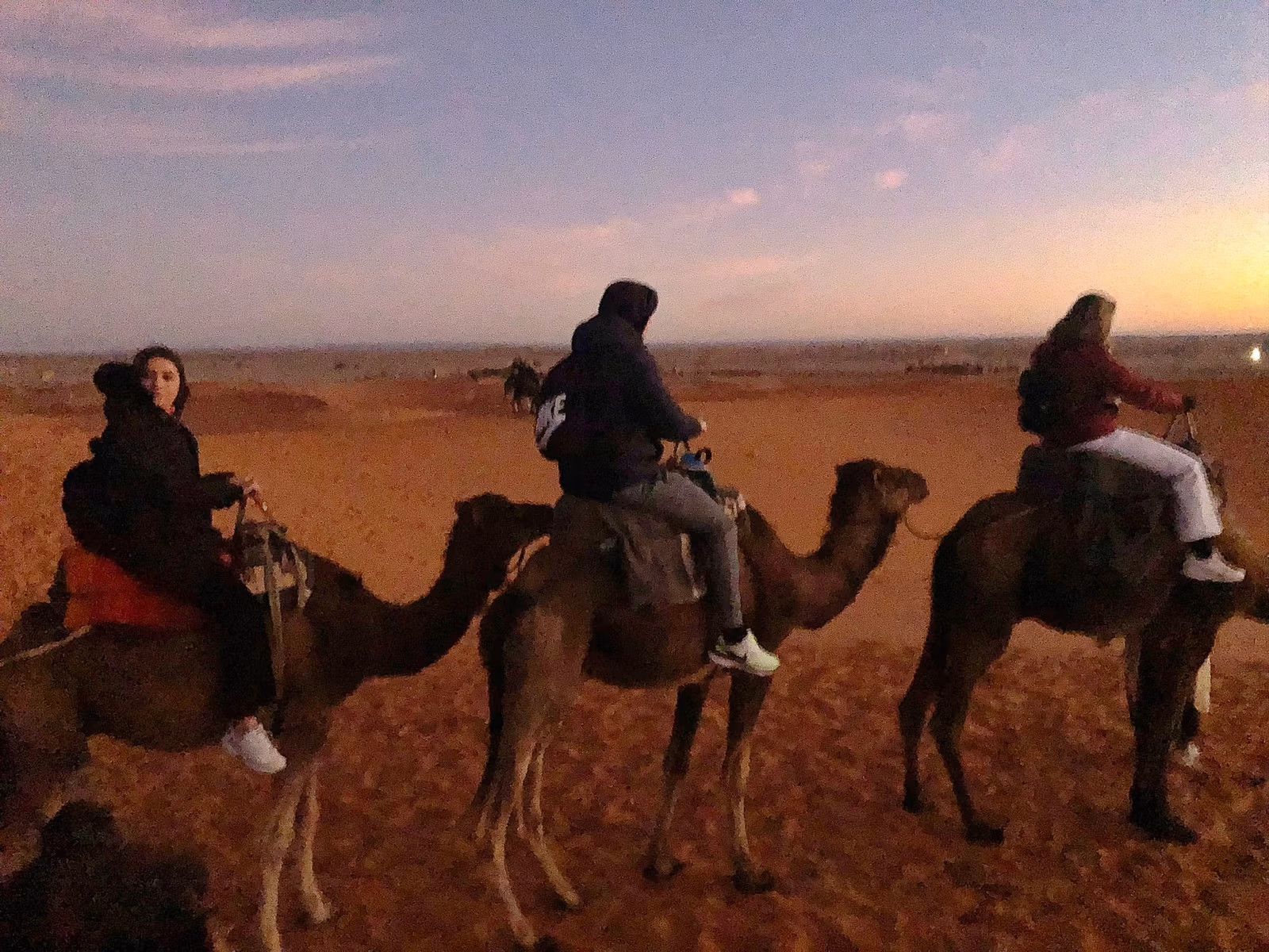 Camel riders silhouetted against the sunset on the Erg Chebbi dunes