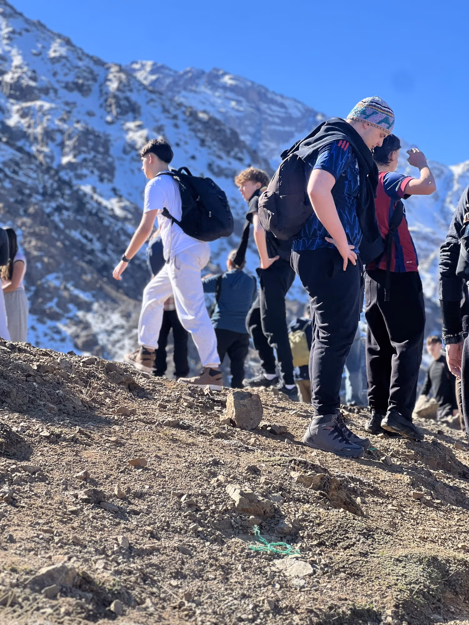 A line of walkers climbing a rocky slope above the Imlil valley