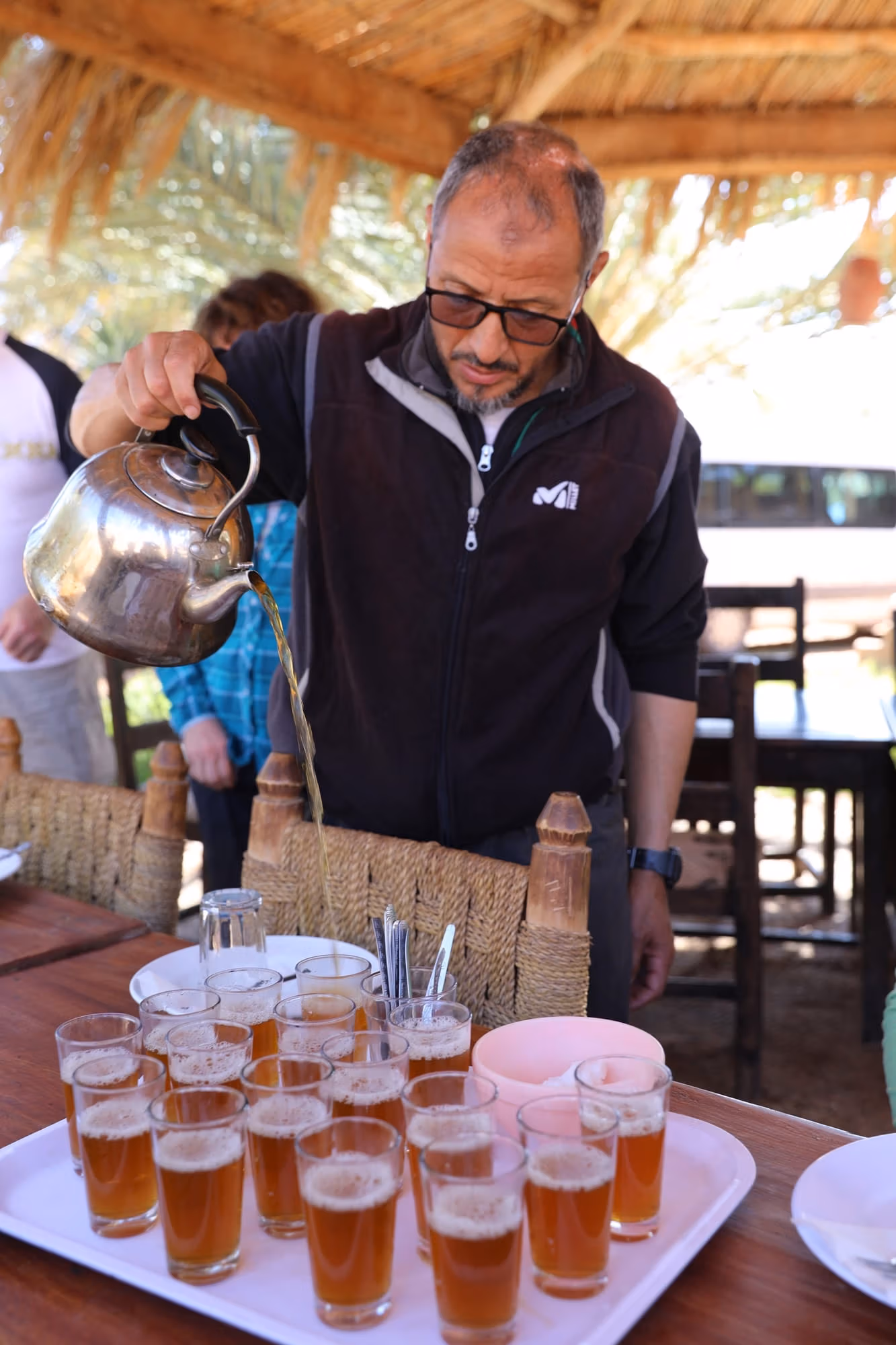Mint tea poured from a height into a tray of glasses