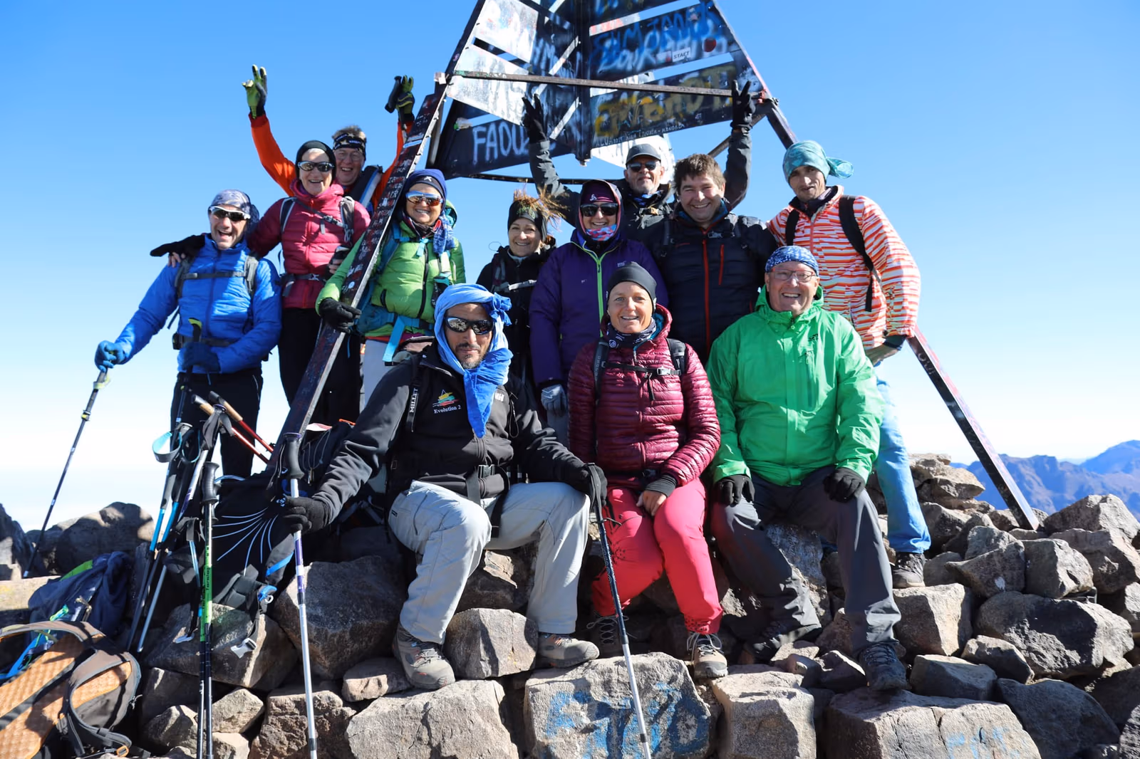 A trekking group gathered around the summit marker of Mount Toubkal